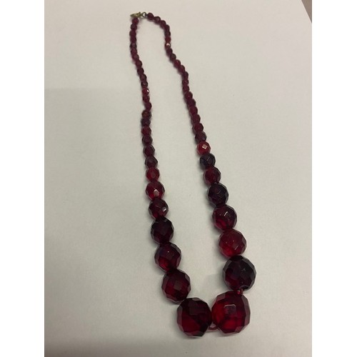 246 - A row of faceted red 'amber' style beads