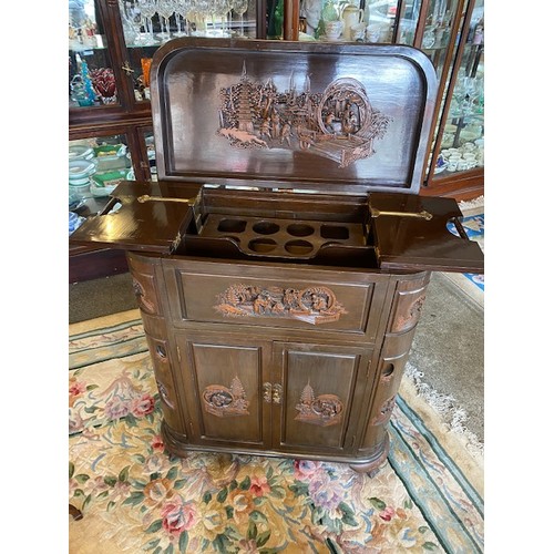 30 - A Chinese cocktail cabinet with hinged lid, carved front above two doors, the rounded ends with carv... 