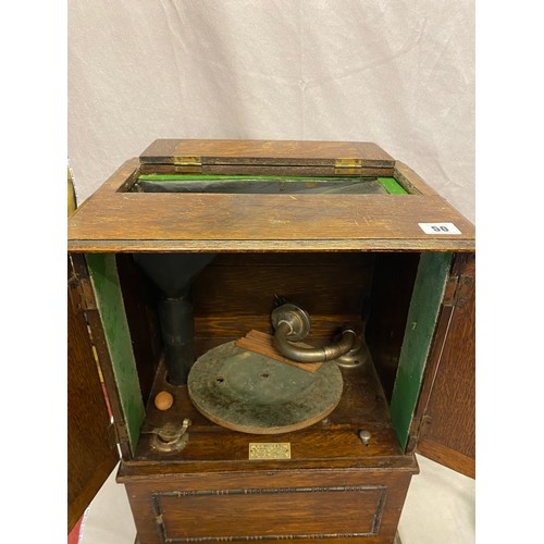 50 - A gramophone retailed by Willis in a small oak cabinet fitted two panelled doors - 14in. wide