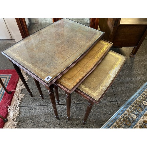 40 - A nest of three reproduction mahogany occasional tables with inset green and gilt tooled tops, on fl... 