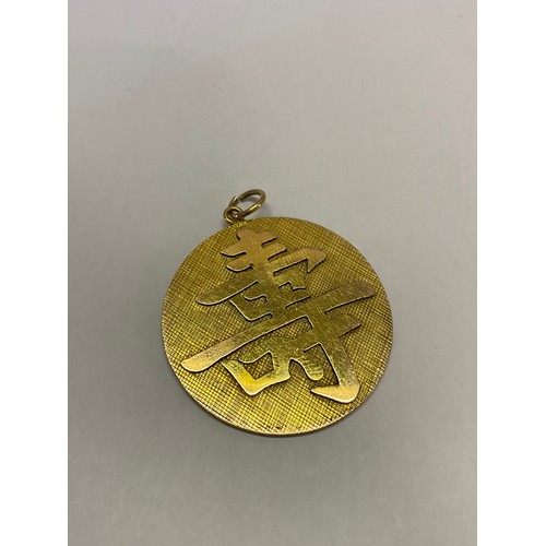 199 - A circular Chinese gold coloured metal pendant, the front set small green oval hardstone