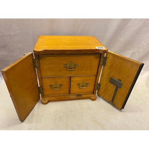 259 - A small oak cabinet in the form of a safe fitted two doors enclosing one wide and two narrow drawers... 