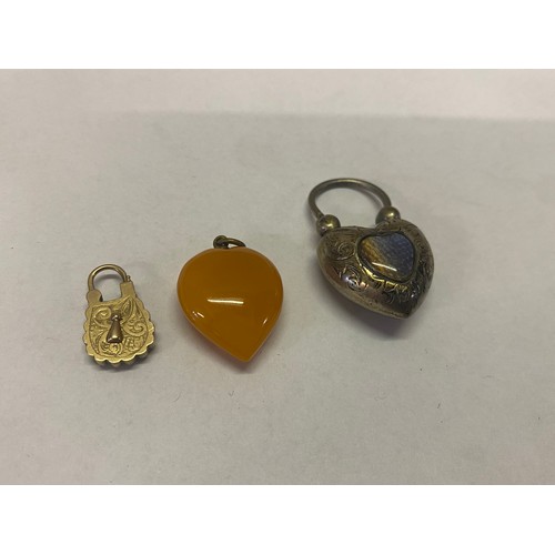 217 - A silver coloured metal heart shaped padlock, an amber style heart shaped pendant and a small gold c... 