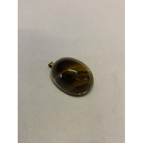 271 - An oval tigers eye set pendant mounted in a 9ct. gold frame