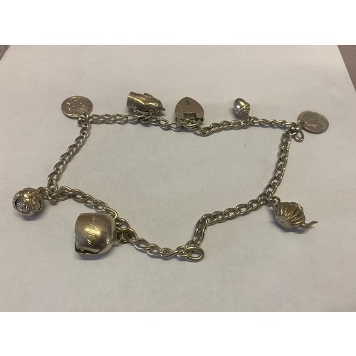 295 - A silver coloured metal bracelet with heart shaped padlock hung with many charms including teapot, a... 