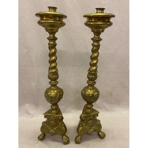 323 - A pair of brass candlesticks with turned columns, angel head decoration, on triangular bases with pa... 