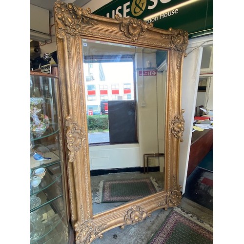 106 - A large reproduction Victorian style bevelled wall mirror in a gilt frame with shell and leaf scroll... 