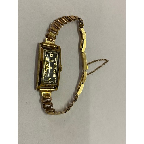 166 - A lady's Swiss wristwatch with rectangular black enamel dial, in a 14kt. gold case, on a 9ct. gold b... 