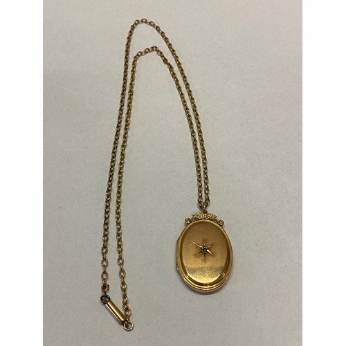 171 - An oval locket with 9ct. gold front and back, set mine cut diamond, on a 15ct. gold chain