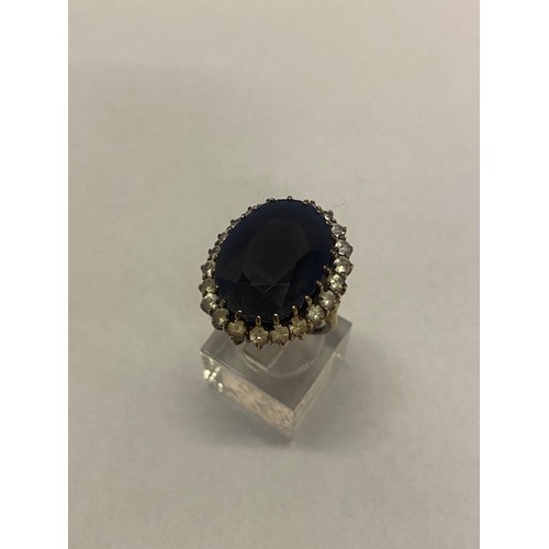 186 - A lady's ring set large sapphire surrounded by white sapphires, on a 9ct. gold shank