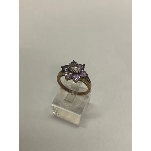 187 - A lady's dress ring of flower form set amethyst coloured stones, on a 9ct. gold shank