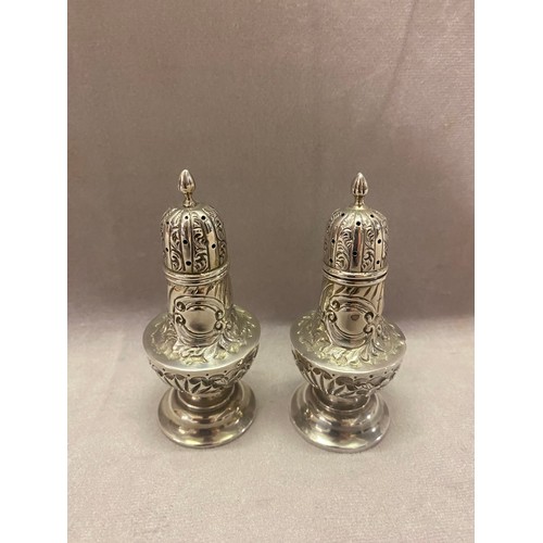 140 - A pair of silver pepperettes with repousse decoration - Chester 1900, makers marks for William Aitki... 