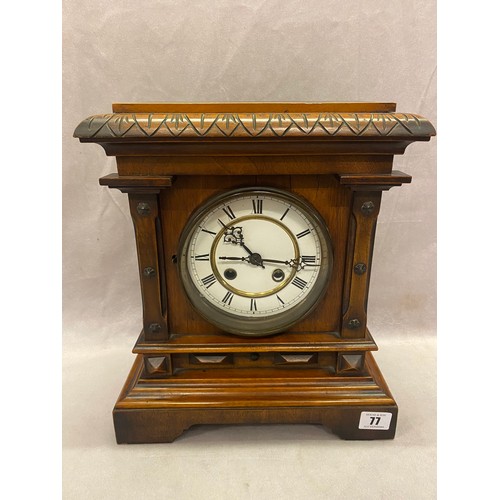 77 - A mantel clock, white enamel dial, striking movement on a gong, in a walnut case - 13in. high