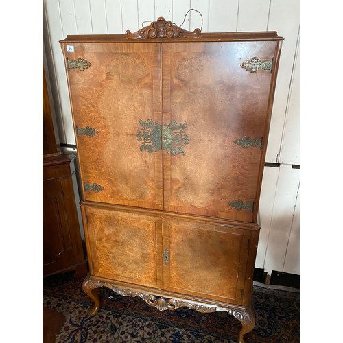 36 - A reproduction walnut veneered cocktail cabinet fitted four doors, on cabriole legs - 42in. wide