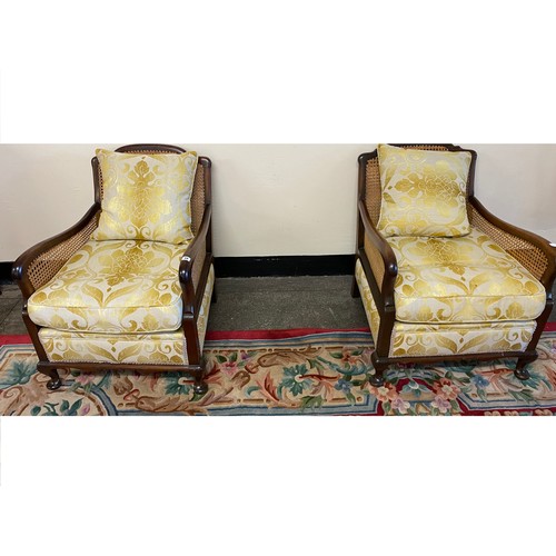 59 - A pair of mahogany finished single cane Bergere chairs with upholstered yellow seats and loose cushi... 