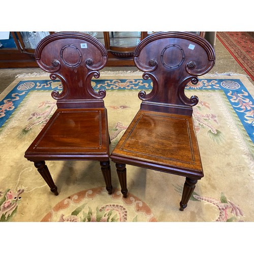 48 - A pair of 19th Century mahogany hall chairs with shaped curved backs, hard seats, on moulded foreleg... 