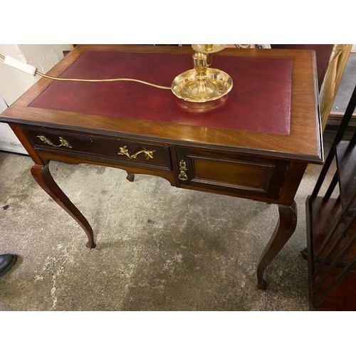 110 - An Edwardian mahogany writing table with red rexine top, fitted frieze drawer and cupboard, on cabri... 