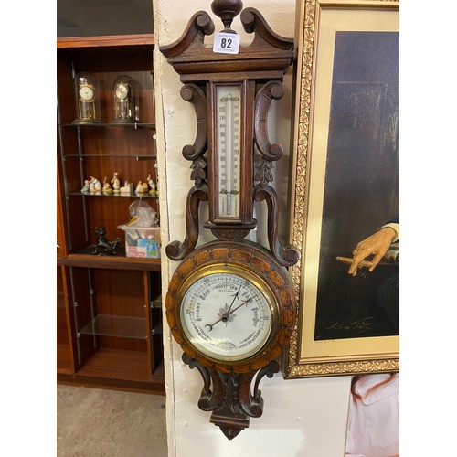 82 - A Victorian aneroid barometer and thermometer on a carved oak mount with scroll pediment