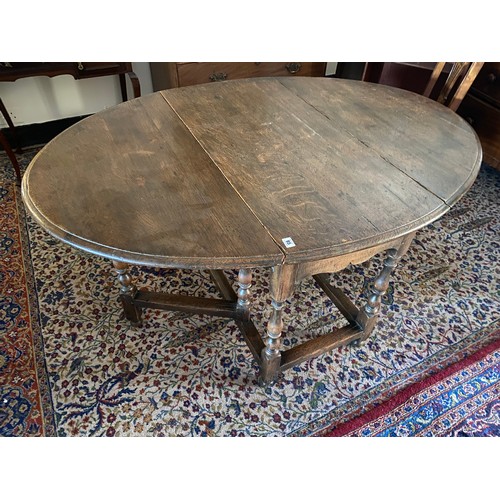 95 - An oak gateleg table fitted two rounded drop flaps, on baluster turned legs united by straight stret... 