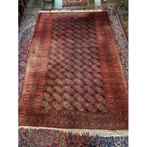 3 - A Bokhara style rug, red field with repeating medallion centre, fringed - 112in. x 73in.