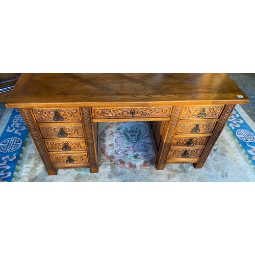 74 - An oak desk fitted centre drawer flanked to each side by four drawers with all over carved decoratio... 