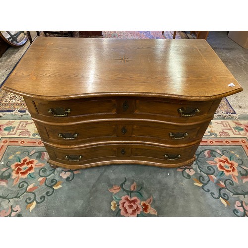 75 - A Continental oak and satinwood inlaid chest with shaped front, fitted three wide drawers, on bracke... 