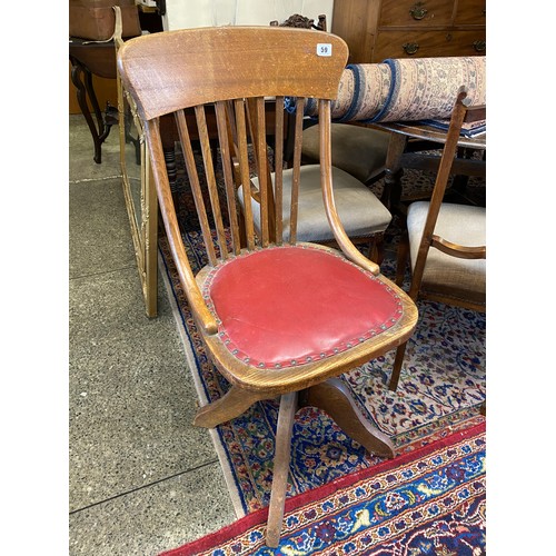 59 - An oak framed revolving desk chair with red studded rexine seat