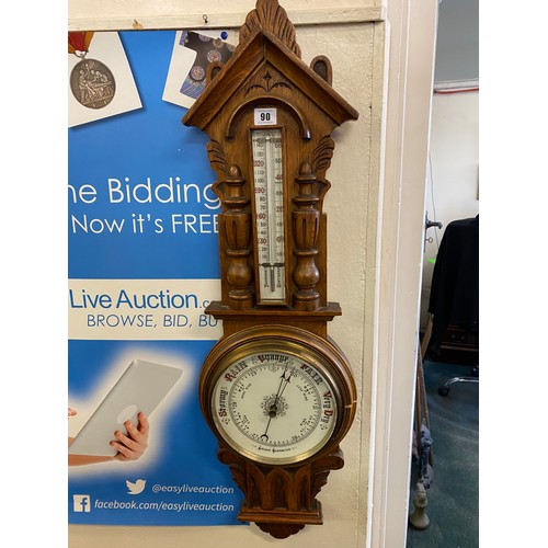 90 - An aneroid barometer and thermometer on a carved oak mount with moulded pilaster decoration