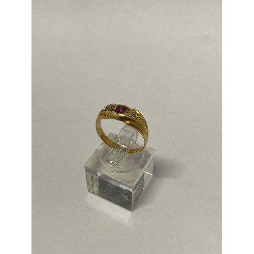 266 - A lady's ring set centre red stone flanked to each side by a diamond, on an 18ct. gold shank