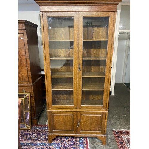 47 - An oak bookcase, the upper part fitted two glass panelled doors, the base fitted two panelled doors,... 