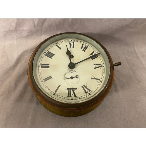 66 - A ships clock with white enamel dial, seconds dial, in a brass case - 7in. dia.