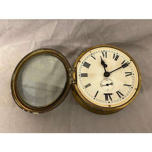 66 - A ships clock with white enamel dial, seconds dial, in a brass case - 7in. dia.