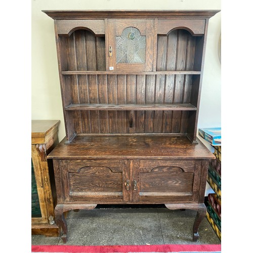 65 - An oak dresser, the raised back fitted leaded glass door and shelves, the base fitted two cupboards,... 