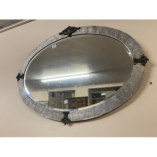 21 - A large oval bevelled wall mirror in a pewter frame - 25in. x 34in.