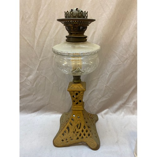 303 - An oil lamp with clear glass reservoir, on gold sprayed iron base