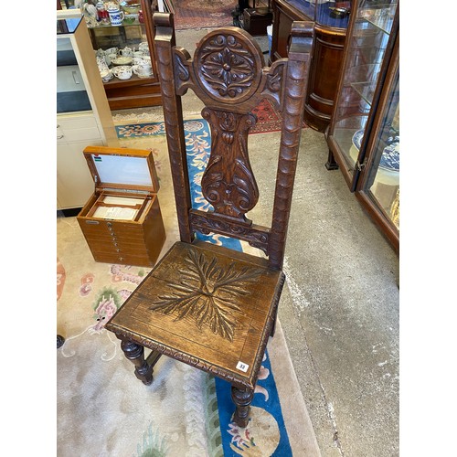 33 - A Victorian oak framed hall chair with leaf carved splat, hard seat, on tapering baluster form legs