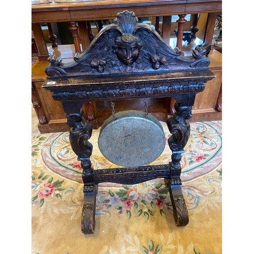 39 - A gong on a Victorian carved oak stand with mask and leaf scroll decoration (no beater)