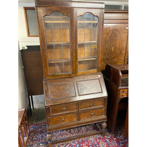 64 - An oak bureau bookcase, the upper part fitted two glass doors, the base with hinged fall front enclo... 