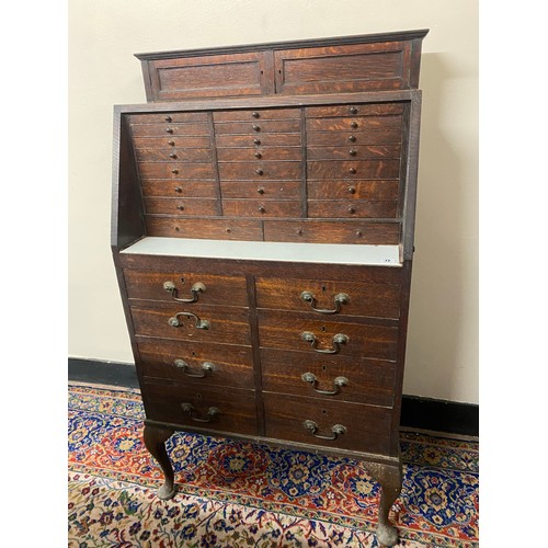 72 - An early 20th Century oak dentists cabinet, the top fitted two small doors above twenty three narrow... 