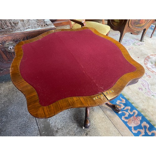 89 - A Victorian walnut veneered card table with serpentine shaped folding top, on turned column, carved ... 