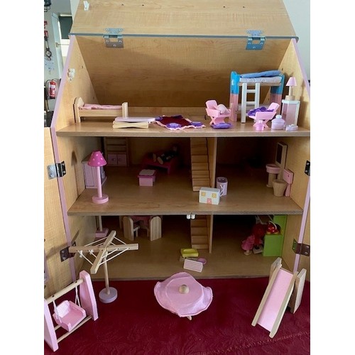 67 - A child's modern wooden dolls house, pink painted, complete with a selection of furniture and figure... 