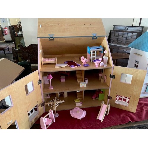 67 - A child's modern wooden dolls house, pink painted, complete with a selection of furniture and figure... 