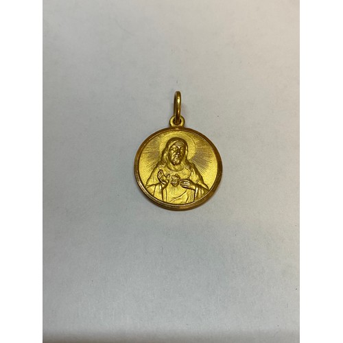 214 - An 18ct. gold pendant depicting Madonna and Child to one side, Christ to the other