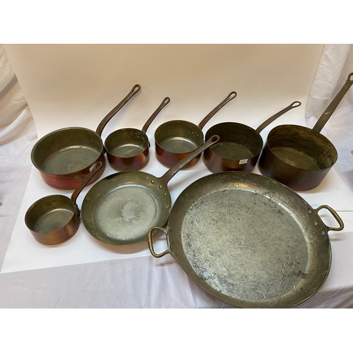 321 - Eight graduated copper pans with iron handles