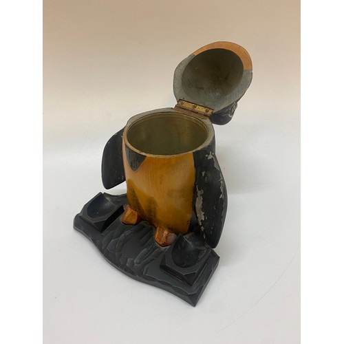 301 - A painted wood tobacco jar in the form of a penguin, the base with two pipe bowl rests - 9in. high