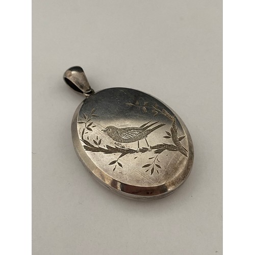 271 - A large Victorian silver locket, the front with engraved decoration of a bird on a branch, the back ... 