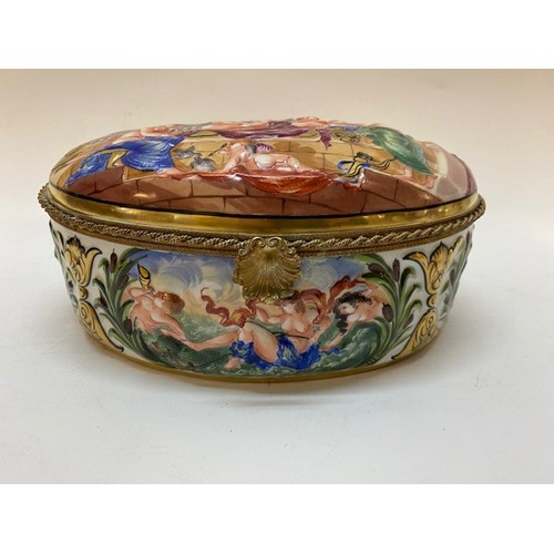 215 - A Capodimonte oval casket decorated to the lid with semi nude figures, putti to the borders within b... 