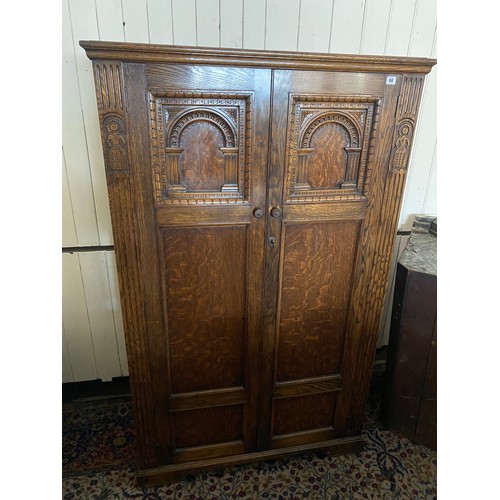 60 - An oak hall wardrobe with carved figures to the sides, two doors with Gothic and linen fold style do... 