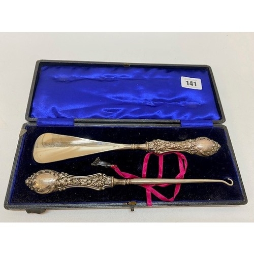 141 - A button hook and shoe horn with repousse decorated silver handles, in fitted case and a selection o... 