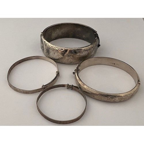 300 - Two silver bangles with engraved decoration and two child's silver bangles  with engraved decoration